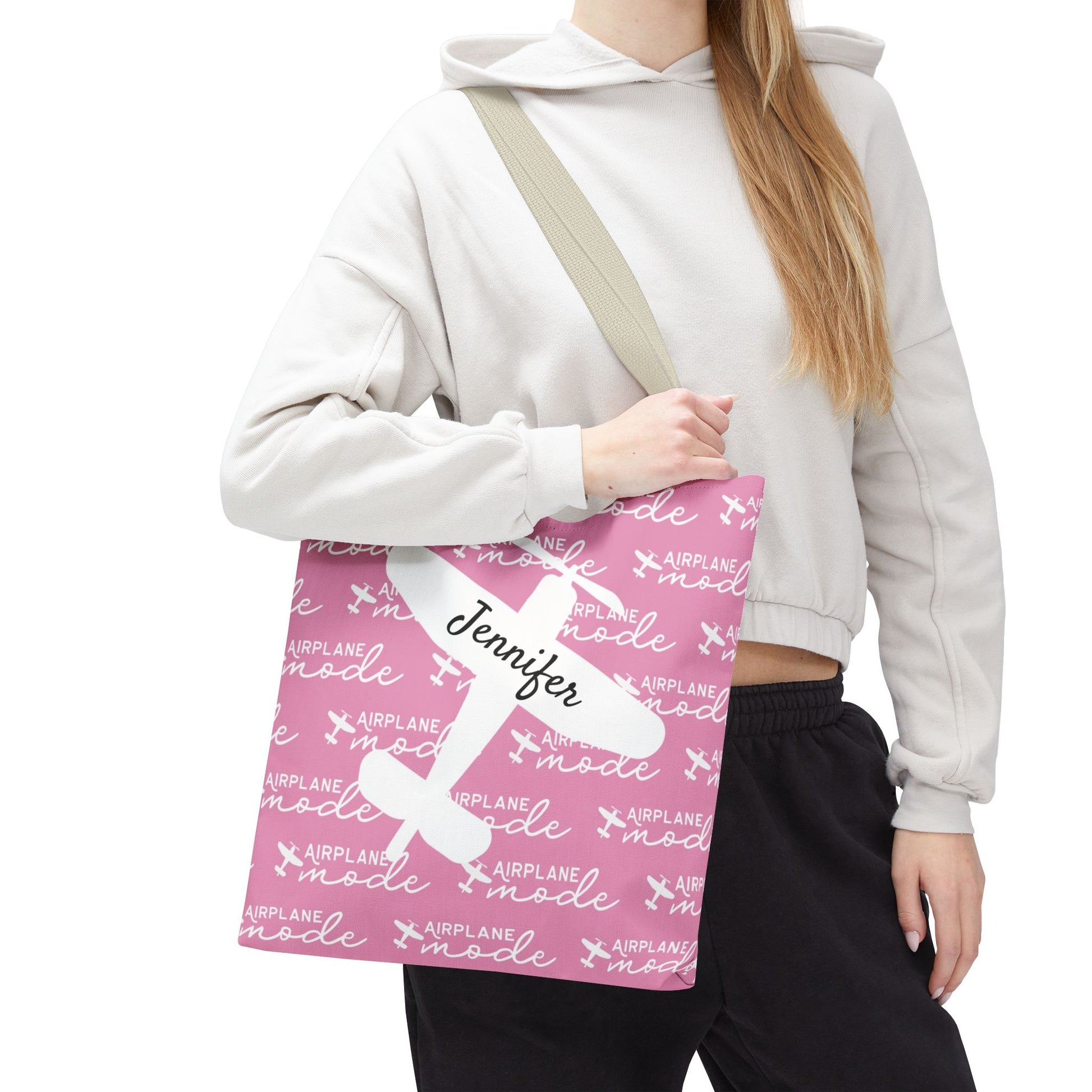 Person holding a pink tote bag with airplane mode text and name 'Jennifer'.