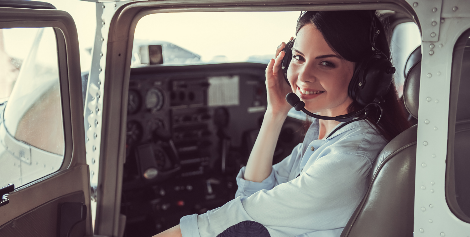 Smiling young wman sitting ina cessna with a headset on